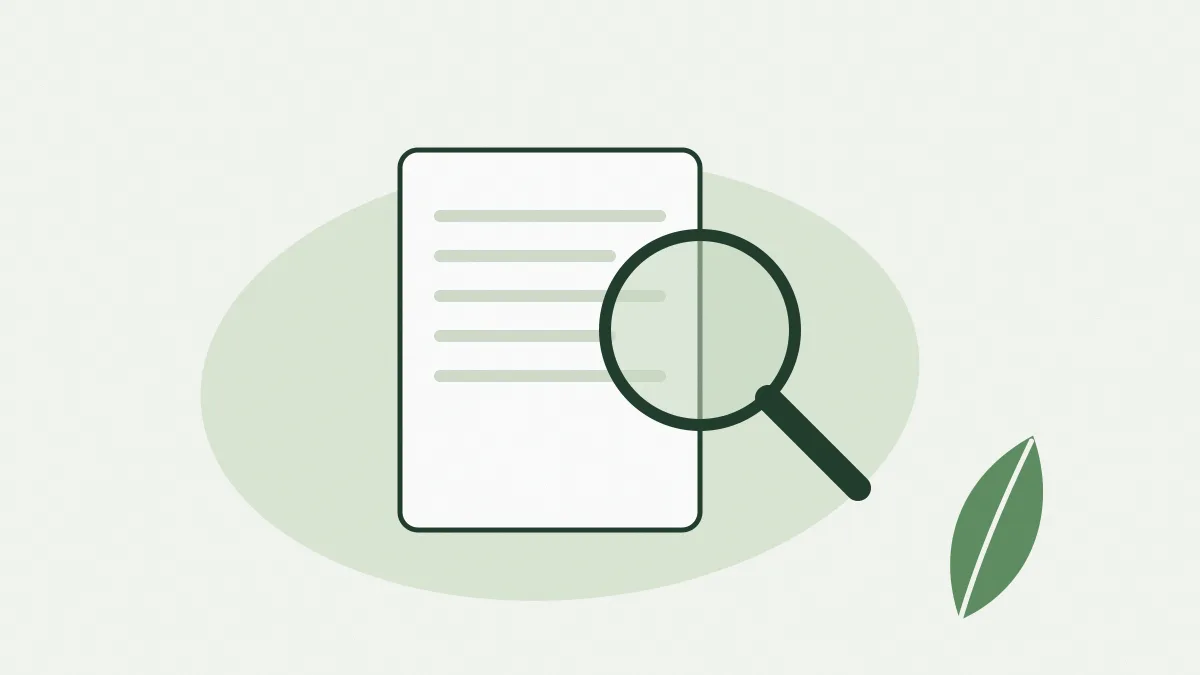 Une loupe posée sur un document, à côté d'une feuille verte